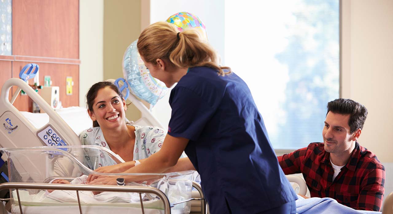Nurse bringing baby to room with mother