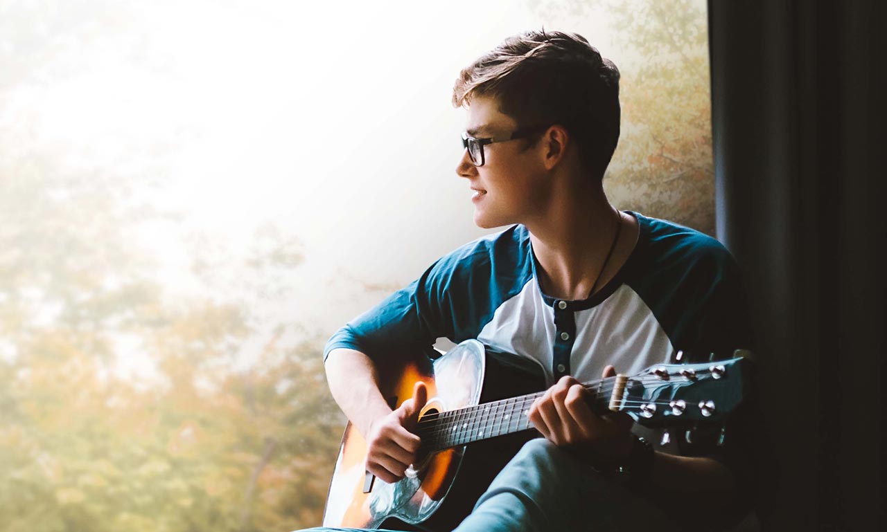 photo of teen laying guitar