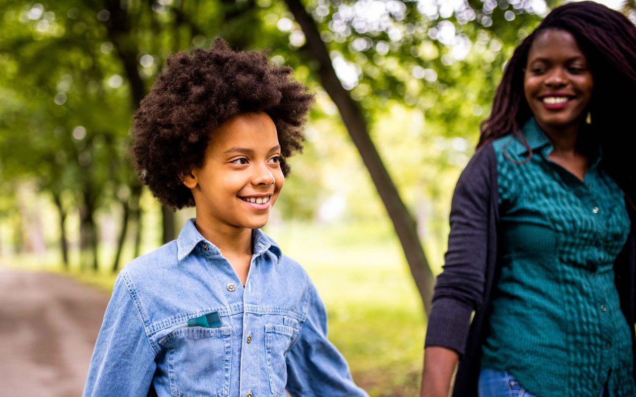 Photo of child walking outdoors with mother