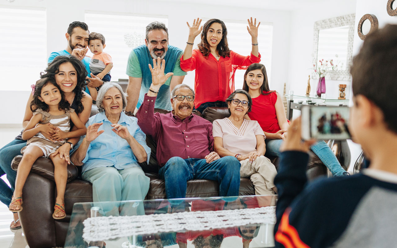 Photo of generational family posing as kid takes a picture with a camera