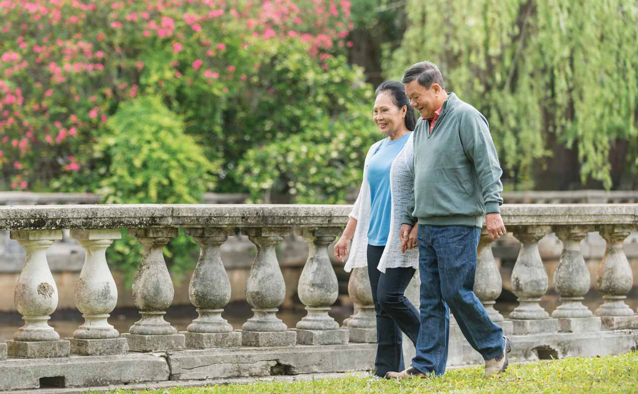 senior couple walking through a park